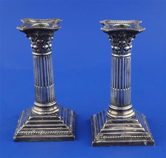 A pair of George V silver corinthian column dwarf candlesticks by William Hutton & Sons, weighted.
